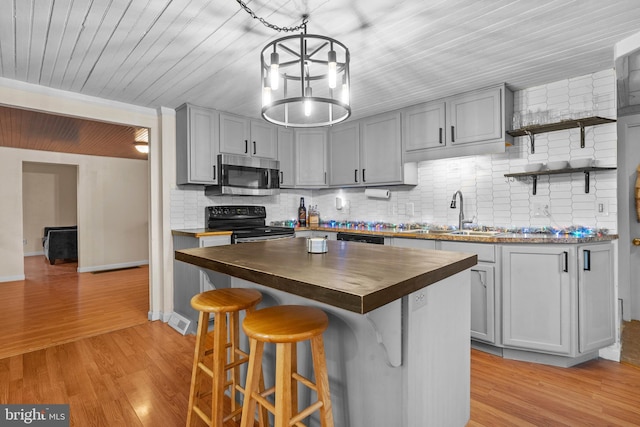 kitchen with wood counters, sink, black appliances, light hardwood / wood-style flooring, and a kitchen island