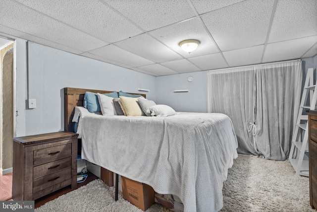 carpeted bedroom featuring a drop ceiling