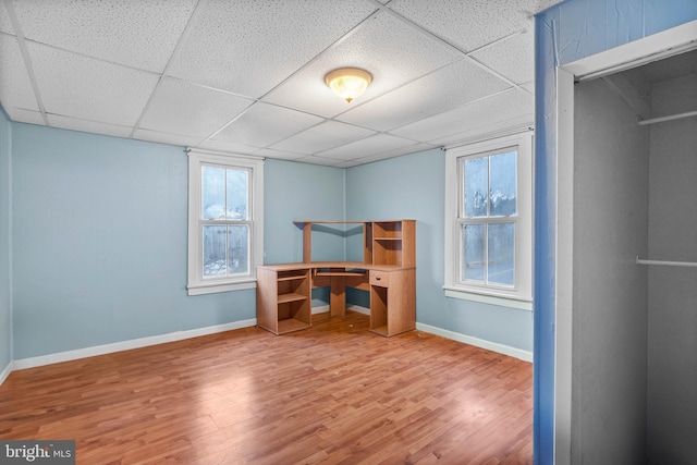 unfurnished bedroom with a paneled ceiling and wood-type flooring