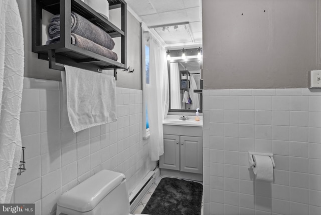 bathroom with vanity, a baseboard radiator, toilet, and tile walls