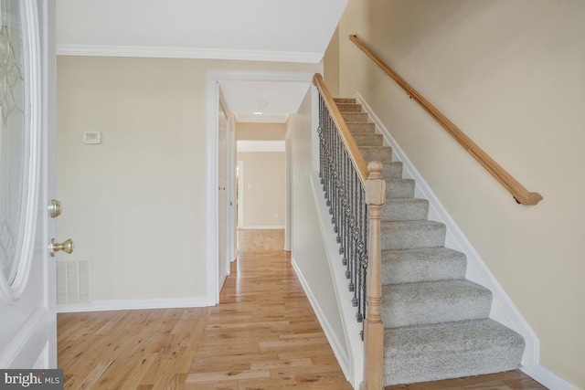 staircase featuring hardwood / wood-style floors and crown molding