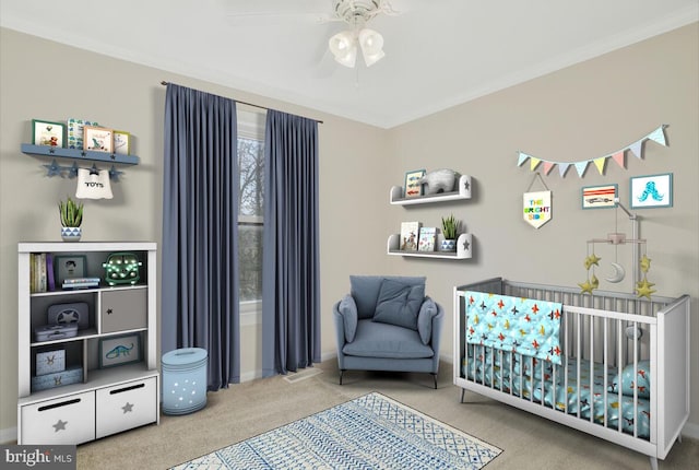 carpeted bedroom with ceiling fan, a crib, and ornamental molding