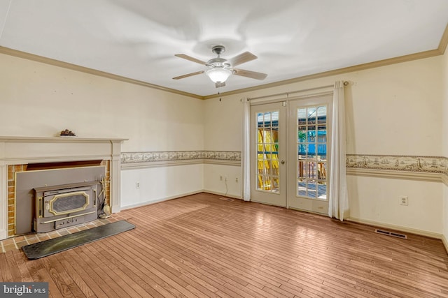 unfurnished living room with a wood stove, ceiling fan, french doors, light hardwood / wood-style flooring, and crown molding