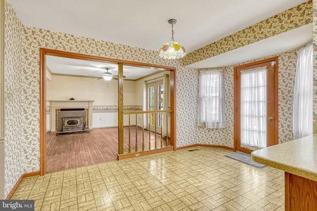 dining room featuring a wood stove, ceiling fan, and crown molding