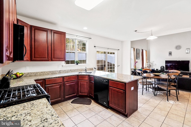 kitchen with light stone counters, light tile patterned floors, black appliances, and decorative light fixtures