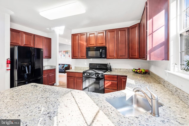 kitchen with light stone countertops, sink, and black appliances