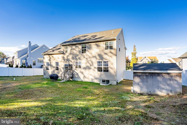 rear view of house featuring a yard and a storage unit