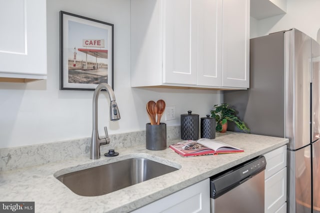 kitchen with dishwasher, light stone countertops, white cabinetry, and sink