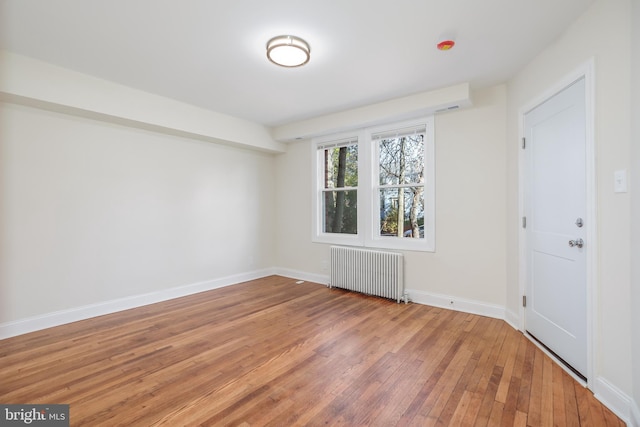 empty room with hardwood / wood-style flooring and radiator