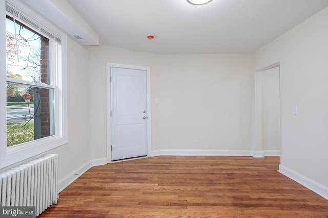 unfurnished room with radiator and wood-type flooring