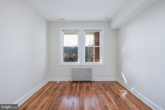 empty room featuring hardwood / wood-style floors and radiator heating unit