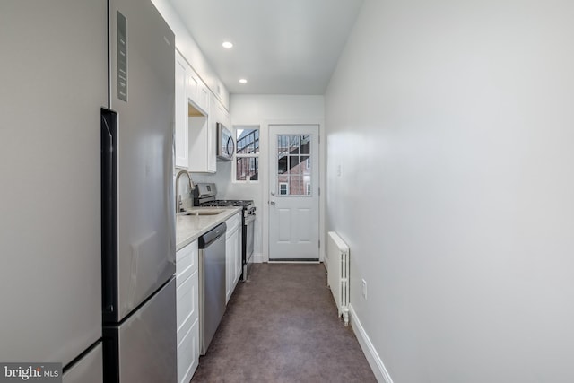 kitchen with white cabinets, sink, carpet flooring, appliances with stainless steel finishes, and radiator heating unit