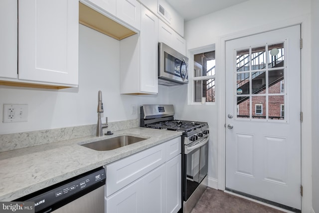 kitchen with white cabinets, light stone counters, sink, and stainless steel appliances