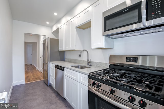 kitchen with light stone countertops, stainless steel appliances, sink, light hardwood / wood-style flooring, and white cabinets