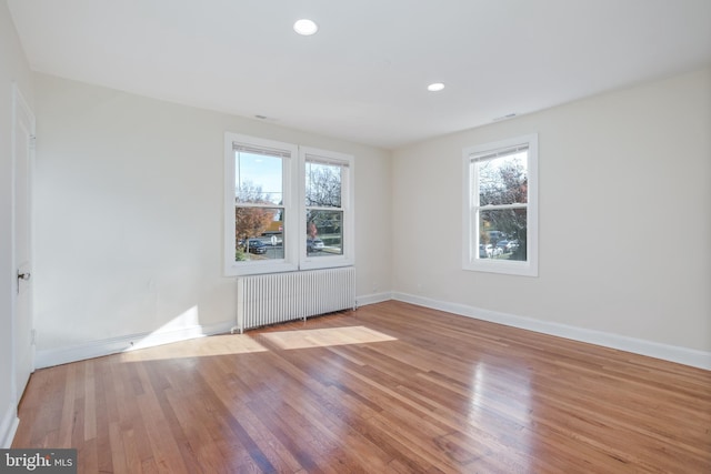 spare room with radiator heating unit, light hardwood / wood-style floors, and plenty of natural light