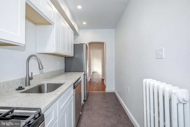 kitchen featuring light stone countertops, stainless steel dishwasher, radiator, sink, and white cabinets