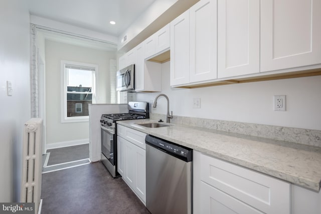 kitchen featuring white cabinets, stainless steel appliances, light stone countertops, and sink