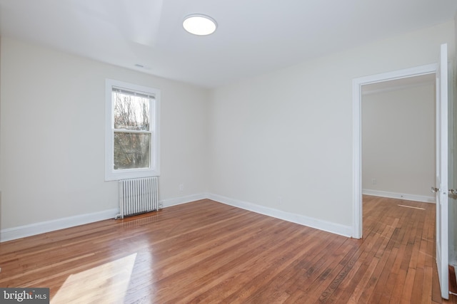 unfurnished room featuring hardwood / wood-style floors and radiator heating unit