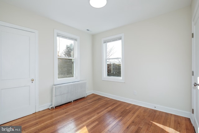 unfurnished bedroom with radiator heating unit and wood-type flooring