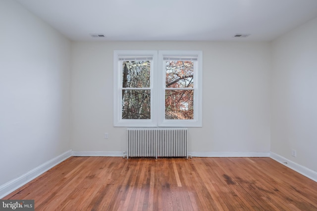 empty room featuring hardwood / wood-style floors and radiator heating unit