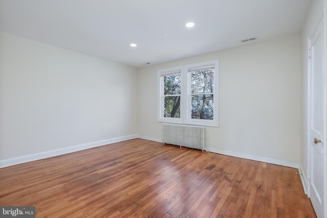 spare room featuring hardwood / wood-style floors and radiator