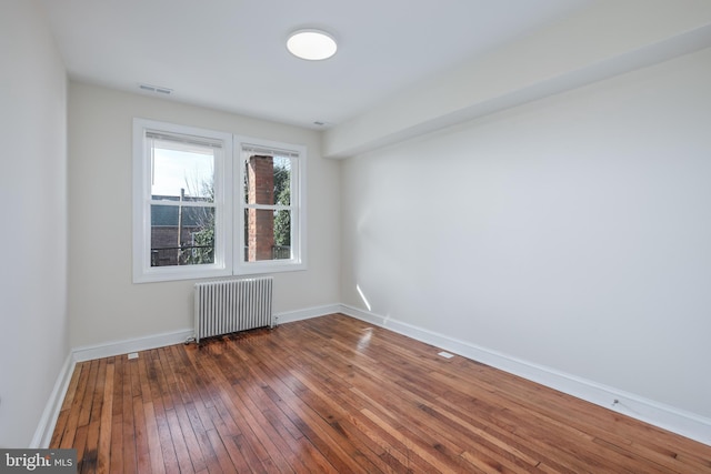 unfurnished room featuring dark hardwood / wood-style floors and radiator