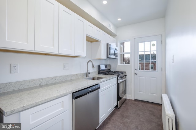 kitchen with radiator heating unit, stainless steel appliances, white cabinetry, and sink