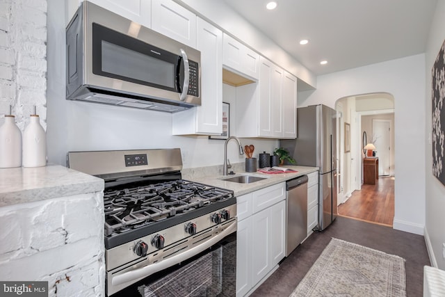 kitchen featuring light stone counters, sink, white cabinetry, and stainless steel appliances