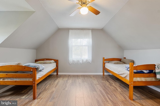 bedroom with ceiling fan, wood-type flooring, and vaulted ceiling