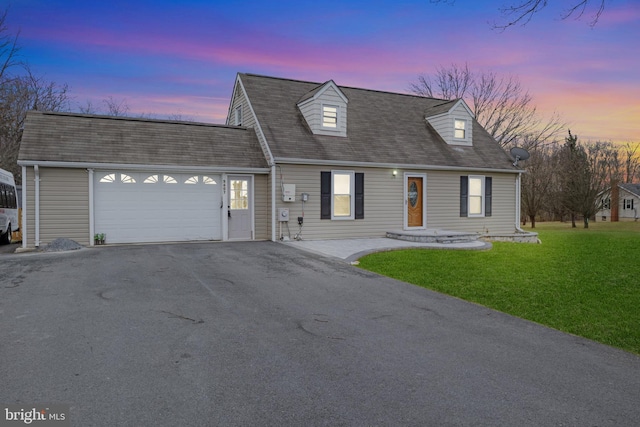 cape cod house featuring a yard and a garage