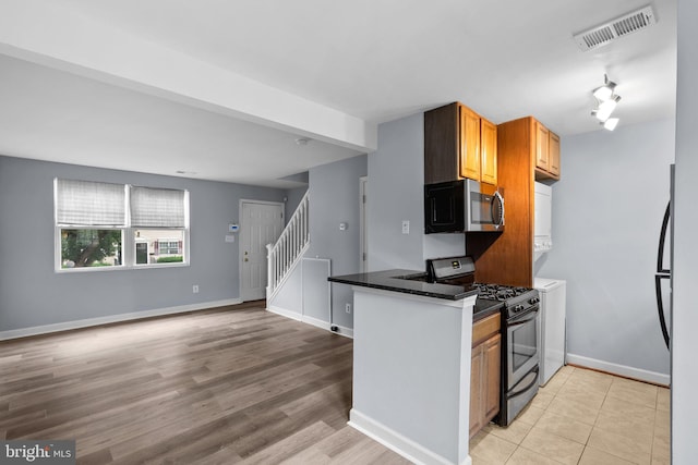 kitchen featuring black gas range oven, dark stone counters, and light hardwood / wood-style flooring