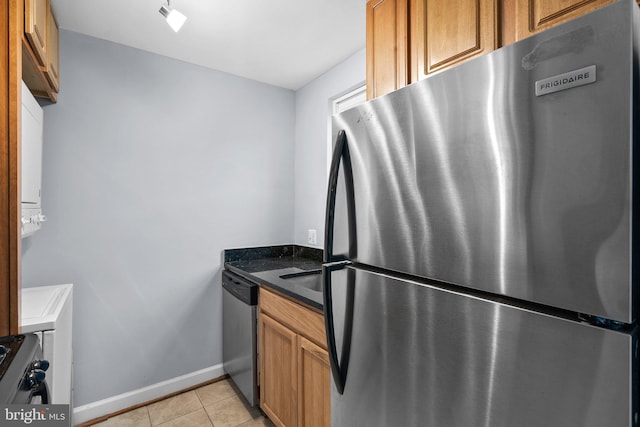 kitchen featuring dark stone countertops, light tile patterned floors, and appliances with stainless steel finishes