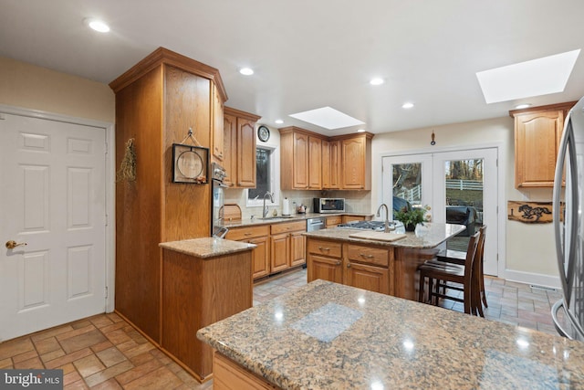 kitchen featuring a kitchen island, light stone countertops, and a skylight