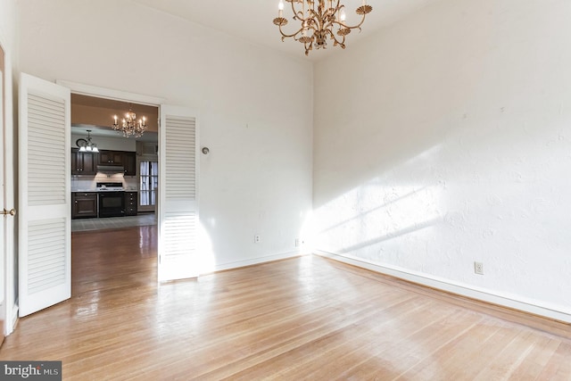 empty room featuring a notable chandelier and wood-type flooring