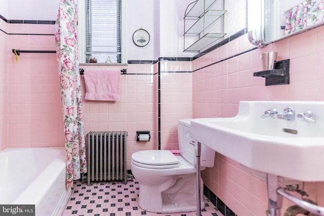 bathroom featuring radiator heating unit, toilet, tile walls, and shower / bath combo