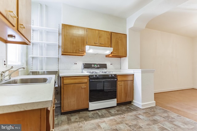 kitchen with decorative backsplash, sink, white stove, and light hardwood / wood-style flooring