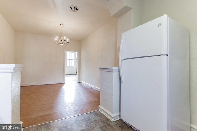 kitchen with white fridge, an inviting chandelier, and hardwood / wood-style flooring