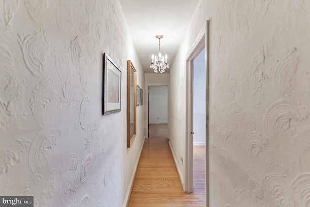 hall with hardwood / wood-style flooring and a notable chandelier