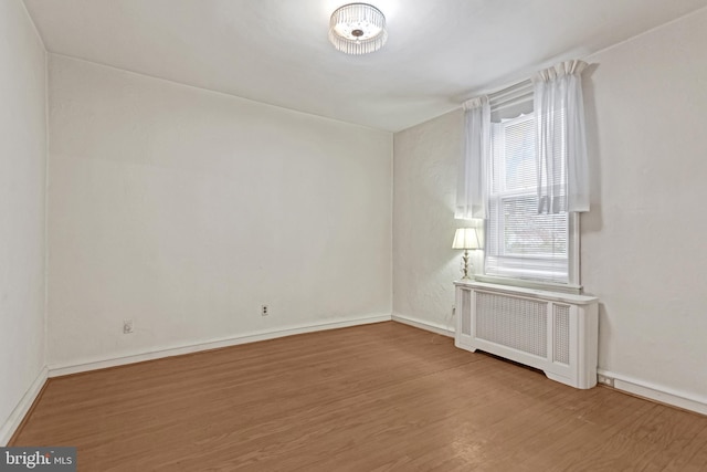 spare room with radiator and hardwood / wood-style flooring