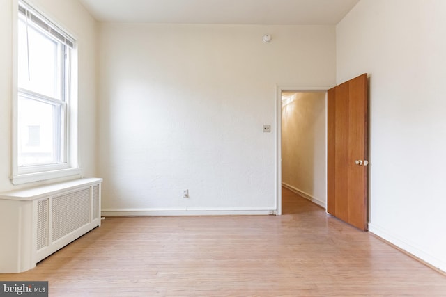 unfurnished room with radiator, a healthy amount of sunlight, and light hardwood / wood-style floors