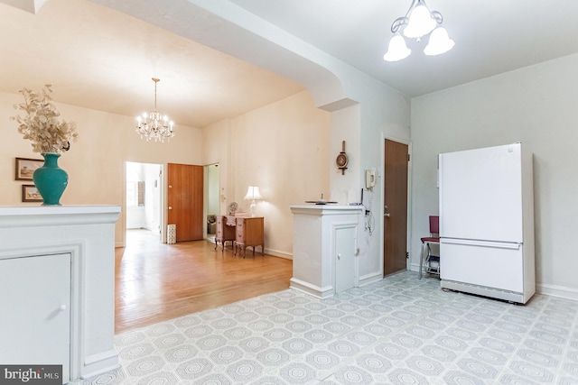 kitchen with decorative light fixtures, white refrigerator, light hardwood / wood-style flooring, and a chandelier