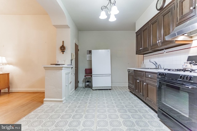 kitchen with dark brown cabinetry, sink, black gas stove, and white refrigerator