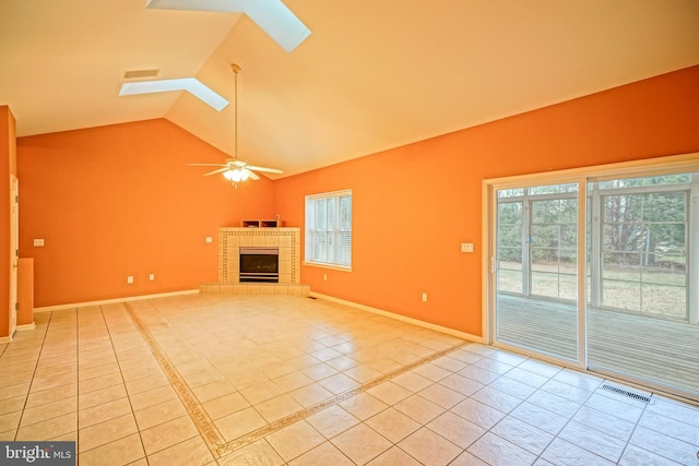 unfurnished living room with a skylight, ceiling fan, a fireplace, and light tile patterned flooring