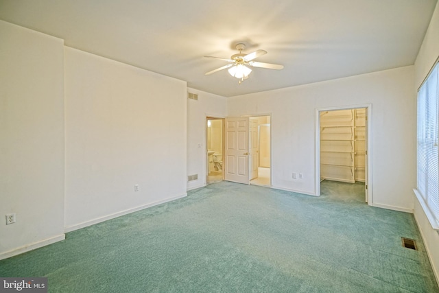 unfurnished bedroom featuring carpet, a closet, a spacious closet, and ceiling fan