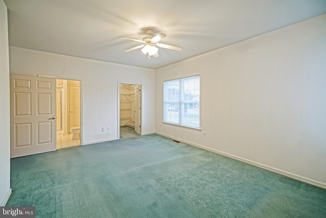 unfurnished bedroom with carpet flooring, ceiling fan, a walk in closet, and a closet