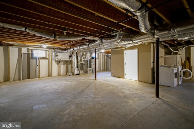 basement featuring heating unit, washer and clothes dryer, and gas water heater