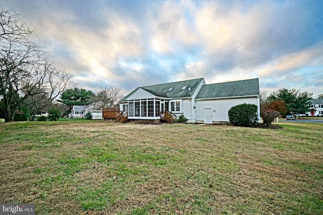 rear view of house featuring a sunroom and a yard