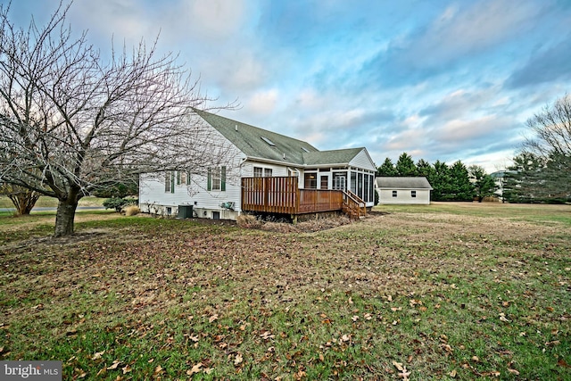 back of property with a sunroom, a lawn, and a wooden deck