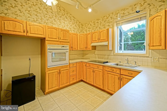 kitchen with light tile patterned floors, vaulted ceiling, oven, and sink