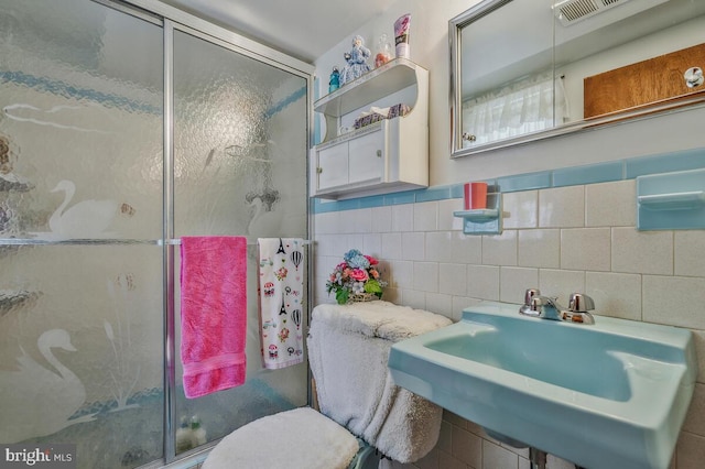 bathroom featuring tile walls, sink, an enclosed shower, and toilet